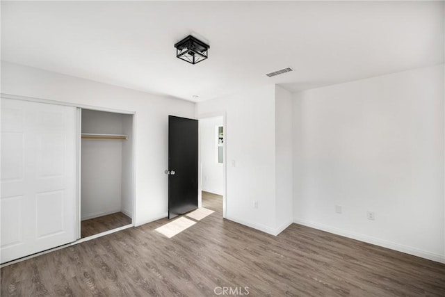 unfurnished bedroom featuring a closet and dark hardwood / wood-style floors