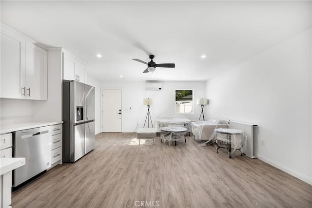 interior space featuring a wall unit AC, ceiling fan, and light wood-type flooring