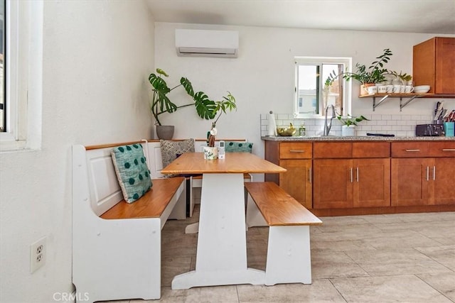 kitchen with breakfast area, tasteful backsplash, a wall unit AC, sink, and light tile patterned flooring