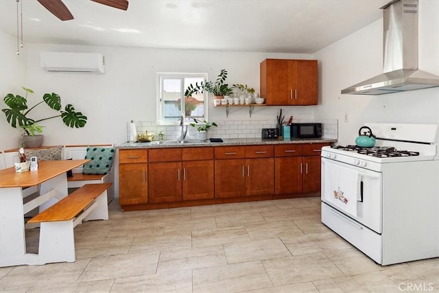 kitchen with a wall mounted air conditioner, decorative backsplash, white range with gas cooktop, sink, and wall chimney range hood