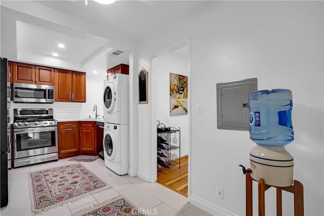 laundry room with sink, electric panel, stacked washer / drying machine, and light tile patterned flooring