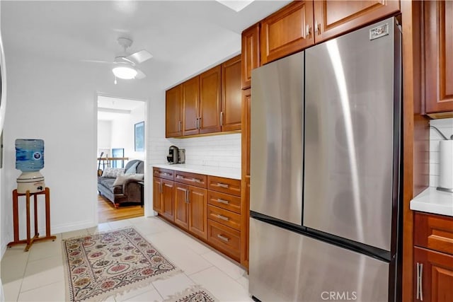 kitchen with tasteful backsplash, stainless steel refrigerator, ceiling fan, and light tile patterned floors