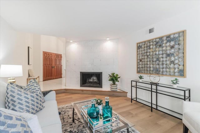 living room with hardwood / wood-style flooring and a tiled fireplace