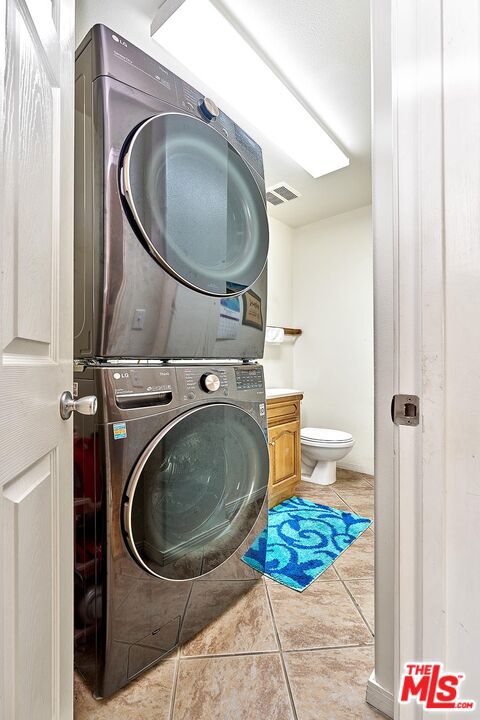 laundry room featuring light tile patterned floors and stacked washer and dryer