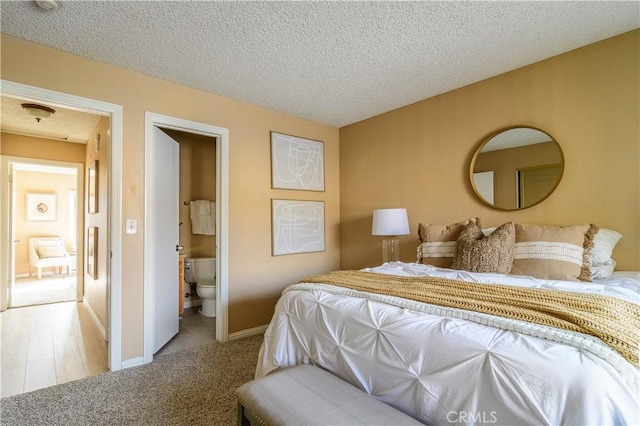 bedroom with a textured ceiling, light carpet, and connected bathroom