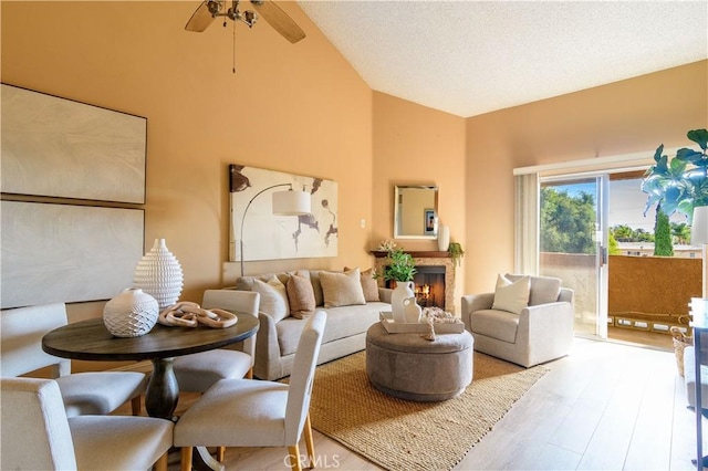 living room featuring hardwood / wood-style floors, ceiling fan, a textured ceiling, and high vaulted ceiling