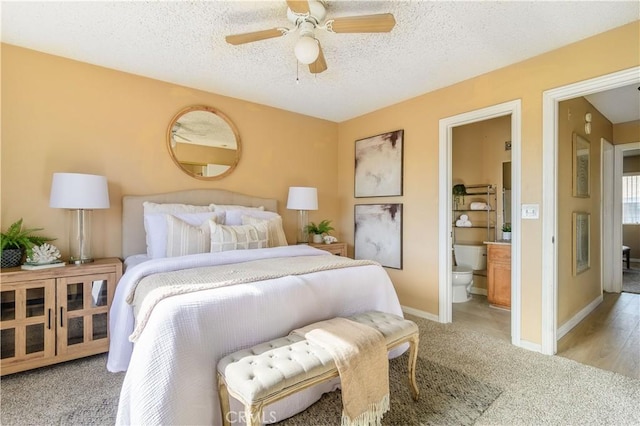 bedroom with ensuite bath, ceiling fan, light hardwood / wood-style flooring, and a textured ceiling