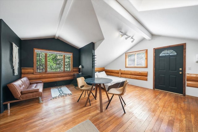 dining area with wood-type flooring and vaulted ceiling with beams