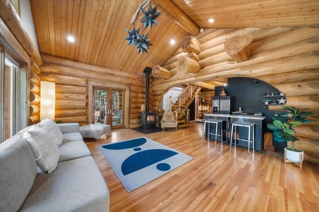 living room featuring lofted ceiling with beams, hardwood / wood-style flooring, rustic walls, and a wood stove