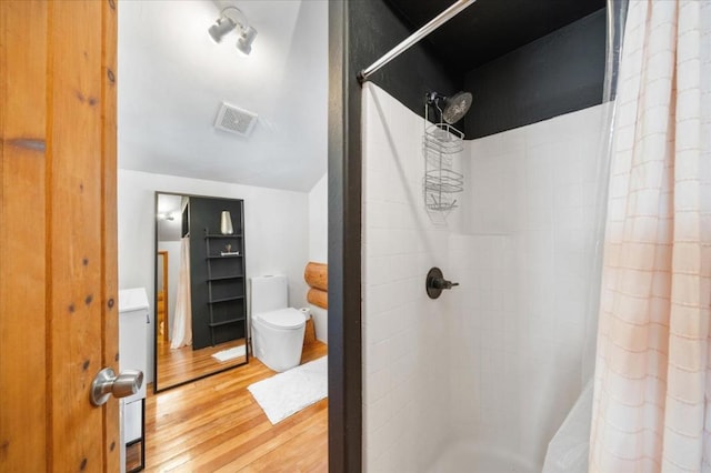 bathroom featuring wood-type flooring, a shower with shower curtain, and toilet