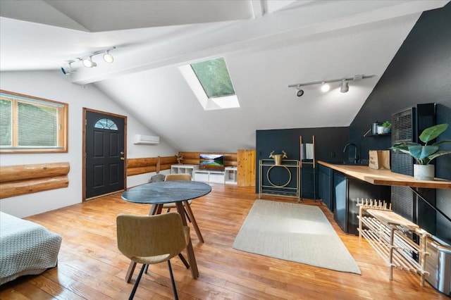 interior space featuring lofted ceiling with skylight, light wood-type flooring, and track lighting