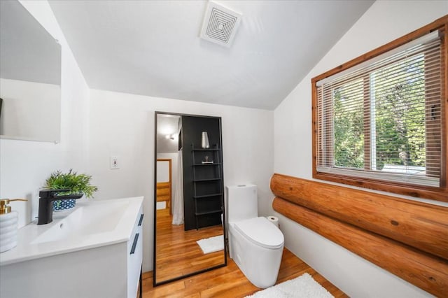 bathroom with vanity, lofted ceiling, hardwood / wood-style floors, and toilet