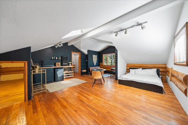 bedroom with lofted ceiling with skylight, rail lighting, and light hardwood / wood-style floors