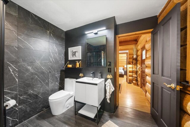 bathroom with vanity, wood-type flooring, wooden walls, tile walls, and toilet