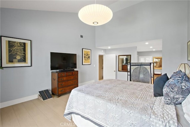 bedroom featuring light wood-type flooring and a towering ceiling