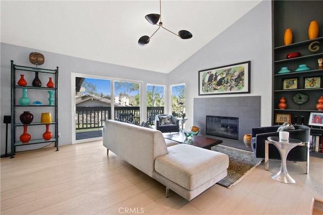 living room featuring a fireplace, built in features, light hardwood / wood-style floors, and high vaulted ceiling