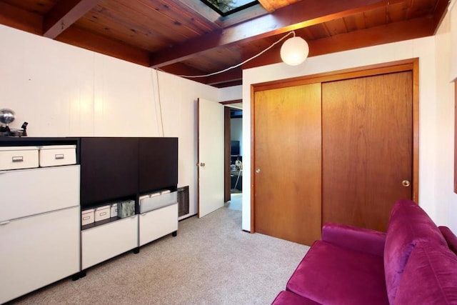 bedroom with beam ceiling, a skylight, light carpet, and wooden ceiling