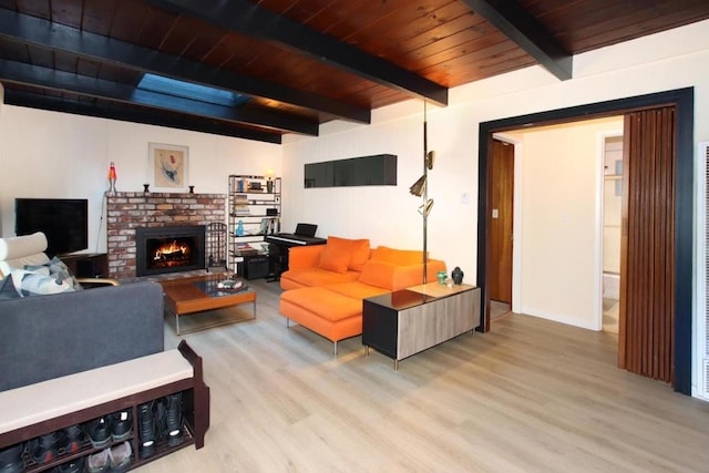 living room featuring a fireplace, beam ceiling, light hardwood / wood-style flooring, and wood ceiling