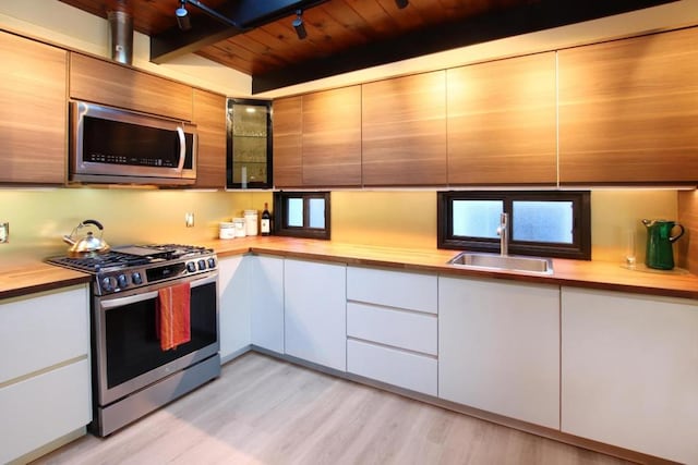 kitchen with wood ceiling, light hardwood / wood-style floors, white cabinetry, and appliances with stainless steel finishes