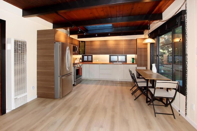 kitchen featuring appliances with stainless steel finishes, light wood-type flooring, pendant lighting, beamed ceiling, and white cabinetry