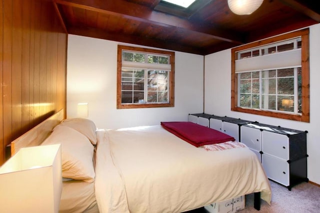 carpeted bedroom featuring beam ceiling and wooden ceiling