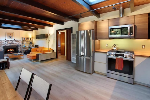 kitchen with a brick fireplace, light hardwood / wood-style floors, beam ceiling, wood ceiling, and stainless steel appliances