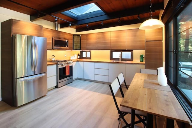 kitchen featuring a wealth of natural light, white cabinetry, stainless steel appliances, and hanging light fixtures