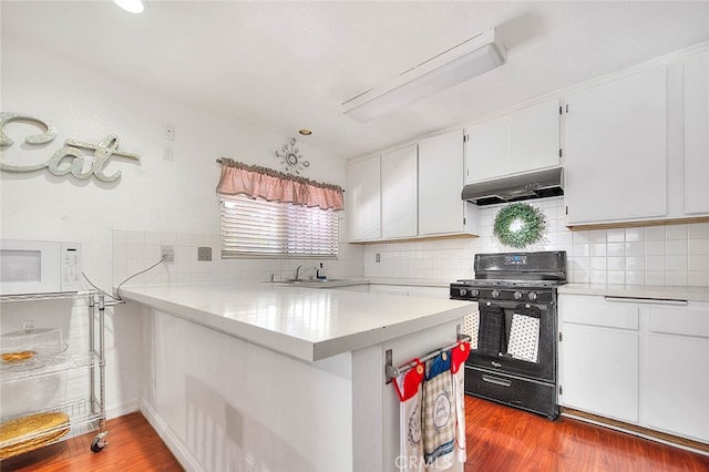 kitchen featuring black range, kitchen peninsula, white cabinetry, hardwood / wood-style flooring, and extractor fan