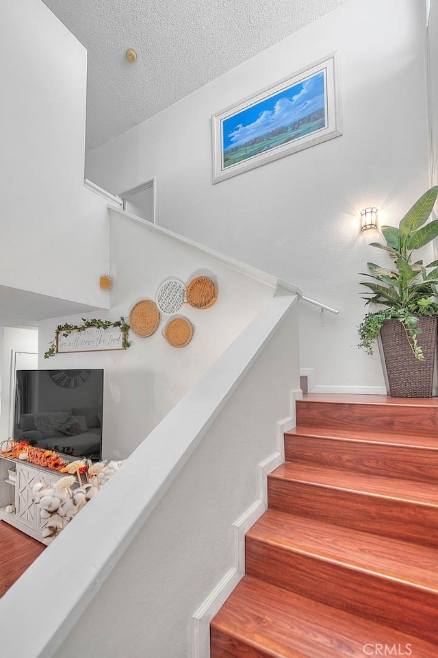 stairs featuring a textured ceiling and hardwood / wood-style flooring