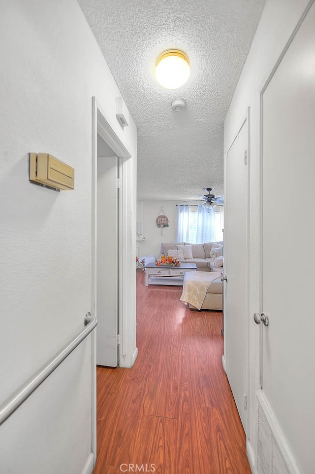 hall with a textured ceiling and hardwood / wood-style flooring