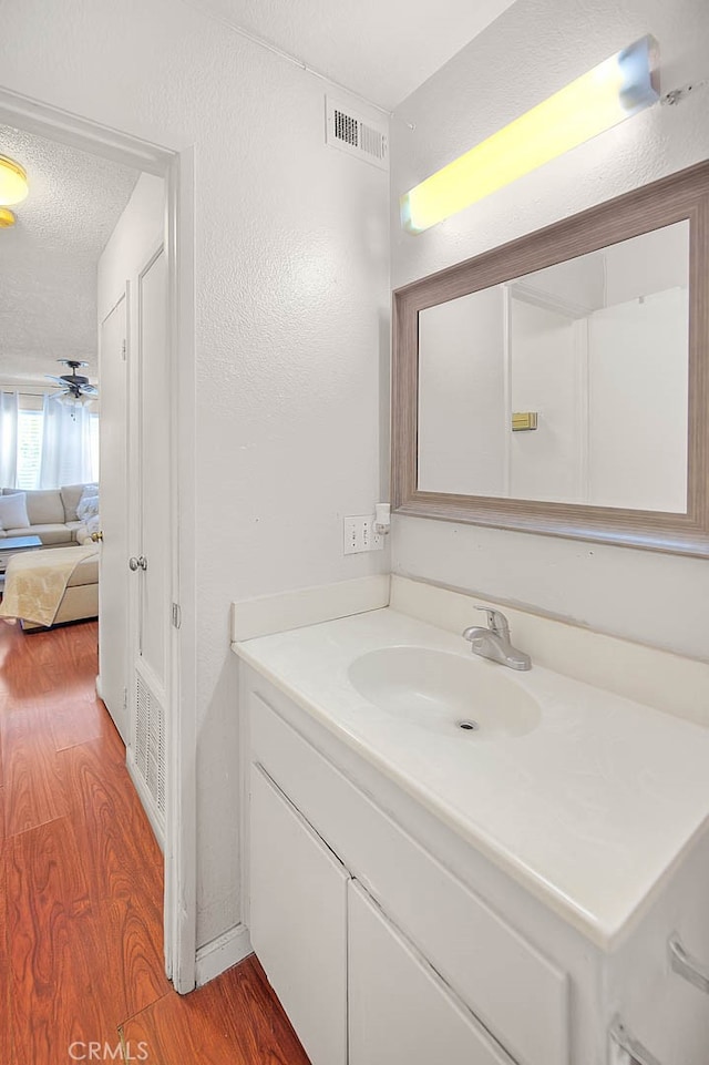 bathroom featuring vanity, a textured ceiling, hardwood / wood-style flooring, and ceiling fan