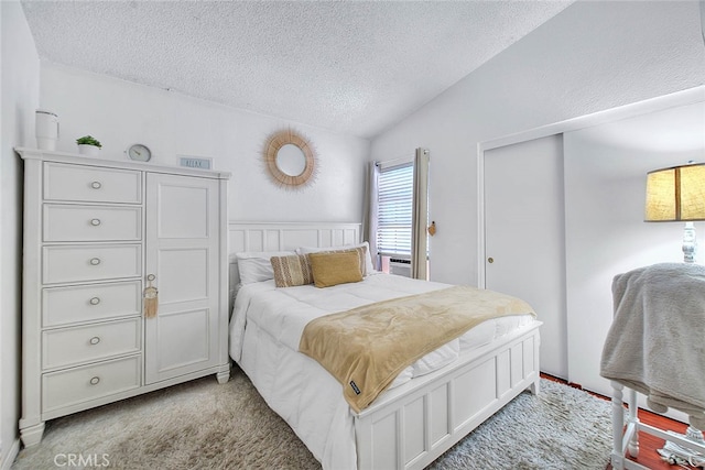 bedroom featuring a textured ceiling, vaulted ceiling, and light colored carpet