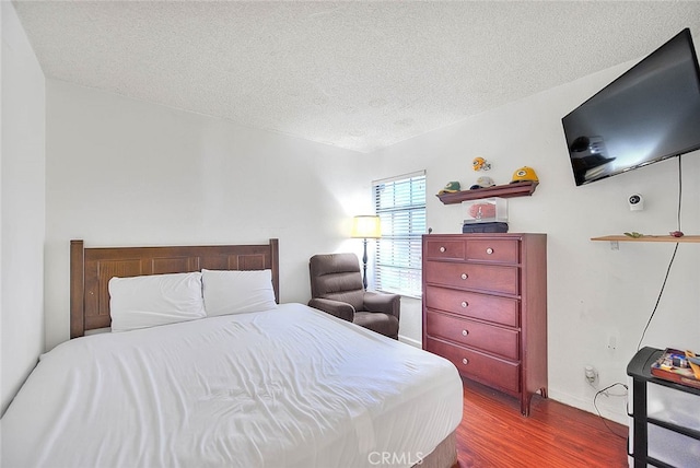 bedroom with hardwood / wood-style floors and a textured ceiling