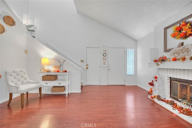 foyer featuring a textured ceiling, hardwood / wood-style flooring, high vaulted ceiling, and a fireplace