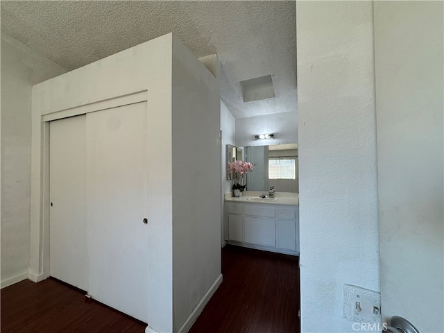 hallway featuring dark wood-type flooring, a textured ceiling, and sink