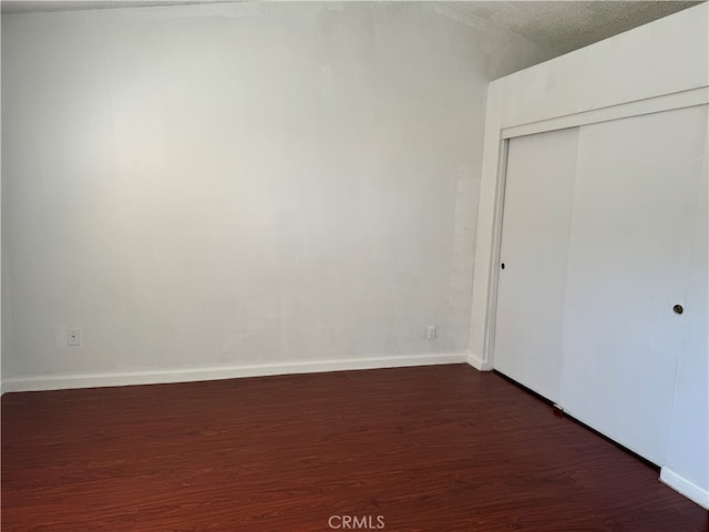 unfurnished bedroom featuring a closet, dark hardwood / wood-style floors, and a textured ceiling