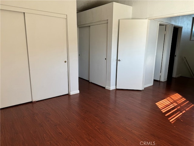 unfurnished bedroom featuring two closets and dark hardwood / wood-style floors