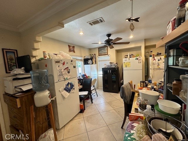 kitchen featuring ceiling fan, white refrigerator, crown molding, and light tile patterned floors