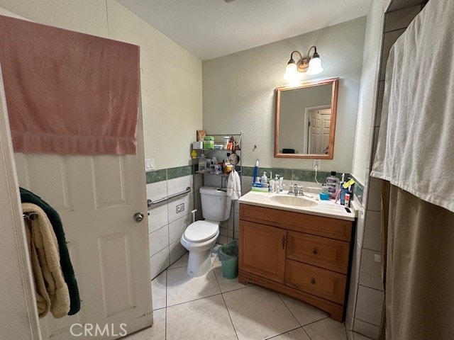 bathroom with tile walls, tile patterned flooring, vanity, and toilet