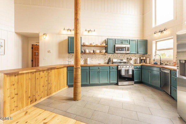 kitchen with butcher block counters, high vaulted ceiling, stainless steel appliances, and light wood-type flooring