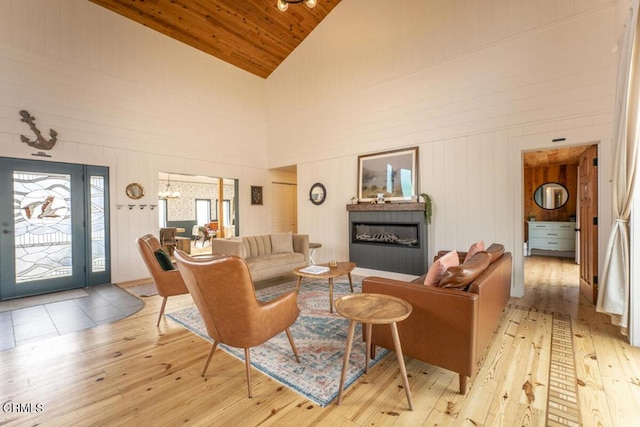 living room with wood walls, high vaulted ceiling, wooden ceiling, and light wood-type flooring