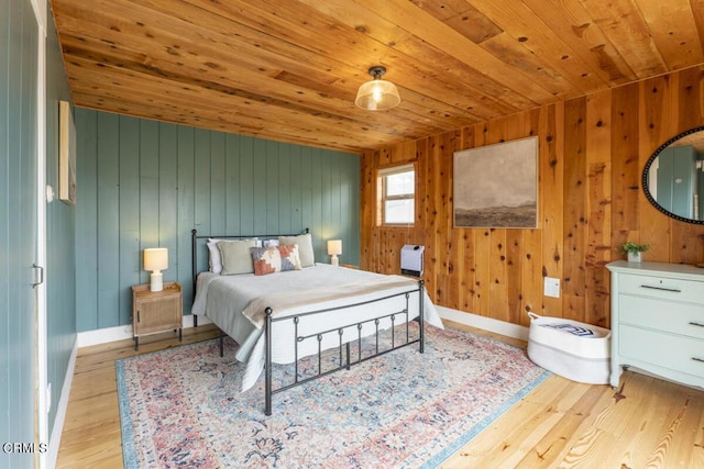 bedroom with light wood-type flooring, wooden walls, and wood ceiling