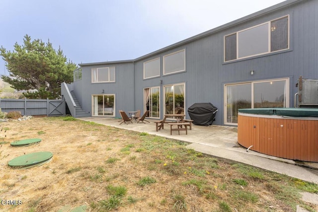 rear view of house featuring a hot tub and a patio area