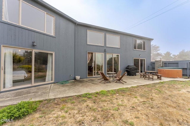 back of property featuring a patio and a hot tub