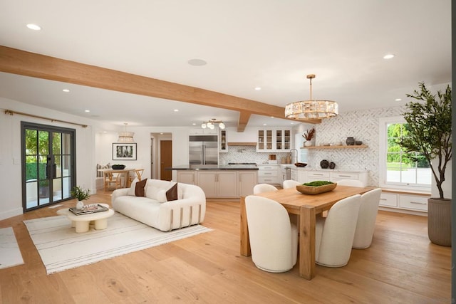 dining space with sink, a chandelier, light hardwood / wood-style flooring, and beam ceiling