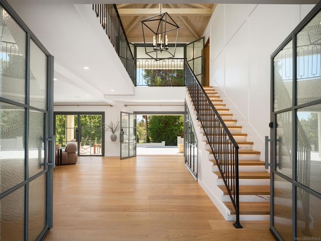 entryway with a chandelier, light wood-type flooring, french doors, high vaulted ceiling, and beam ceiling