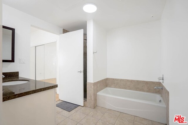 bathroom with a bathing tub, tile patterned flooring, and vanity