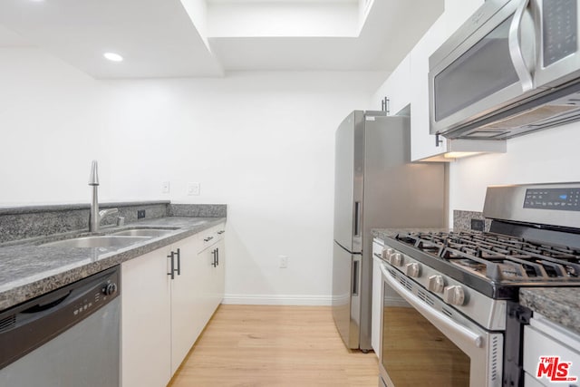 kitchen with sink, white cabinets, light hardwood / wood-style floors, and appliances with stainless steel finishes