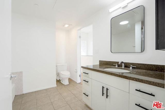 bathroom featuring tile patterned flooring, vanity, toilet, and a tub