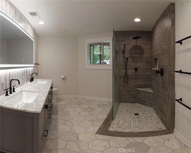 bathroom featuring a tile shower, vanity, toilet, and tile patterned floors